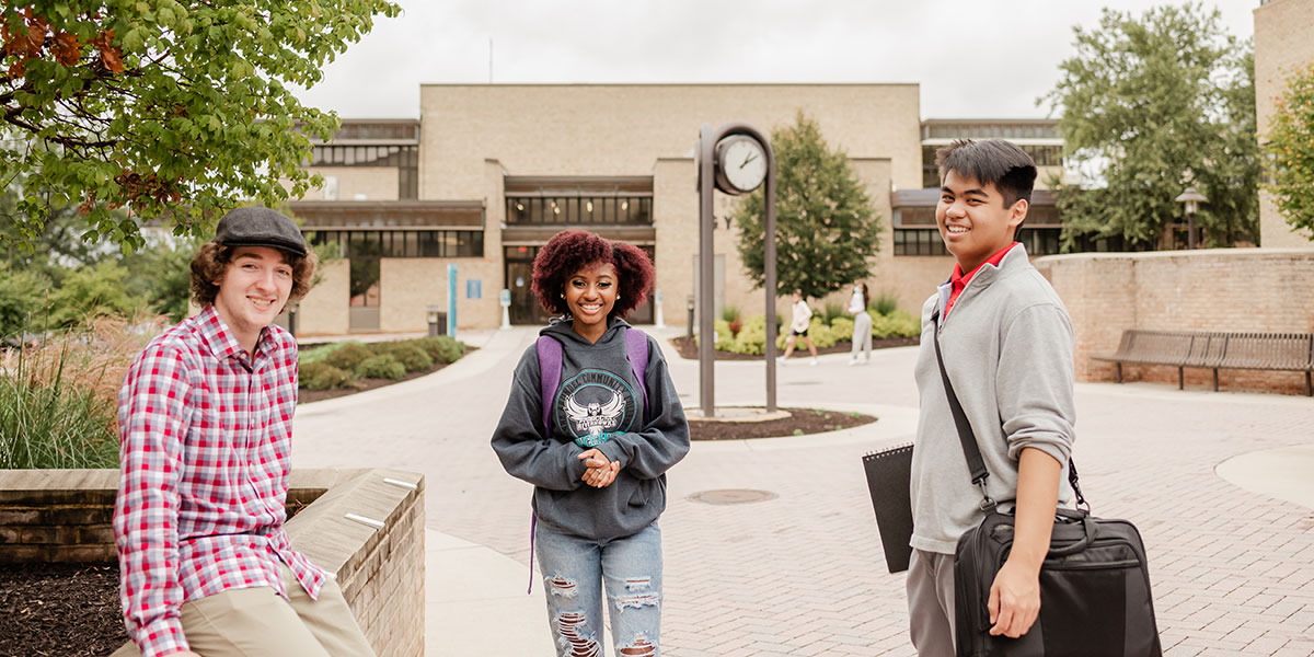 Three students standing in front of gymnasium on campus