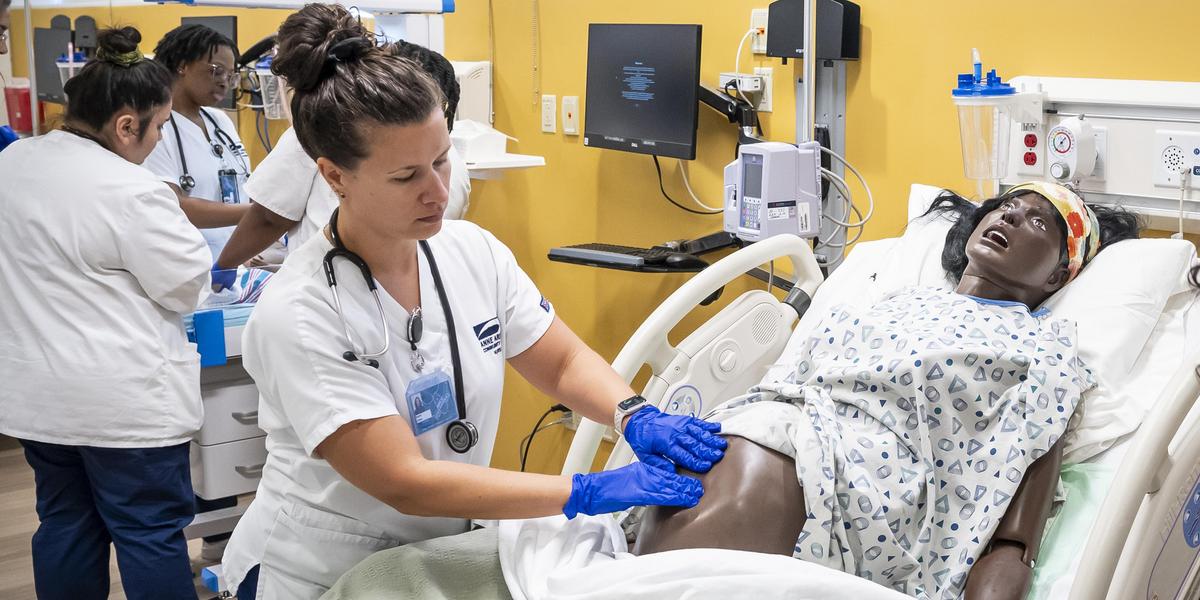 Nursing student working with pregnant manikin.