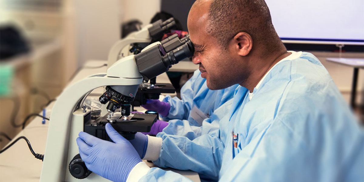 AACC health science student using a microscope.