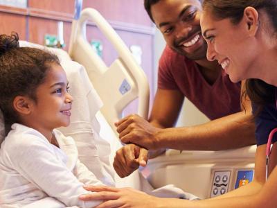 Health care professional at bedside of pediatric patient.