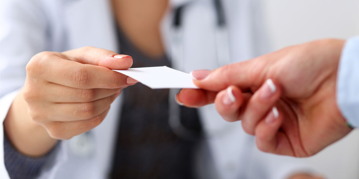 Health care professional hands patient their insurance card.