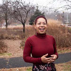 Professor April Copes, wearing a red turtleneck and standing outside on campus