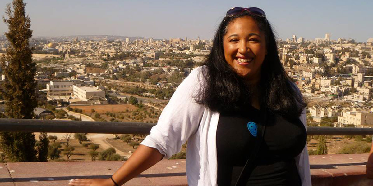 AACC professor, Jamila Barton, posing with a cityscape in the background.