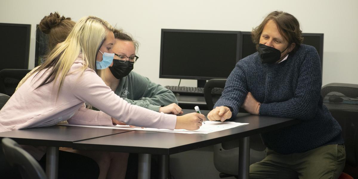 Professor assisting students in classroom.