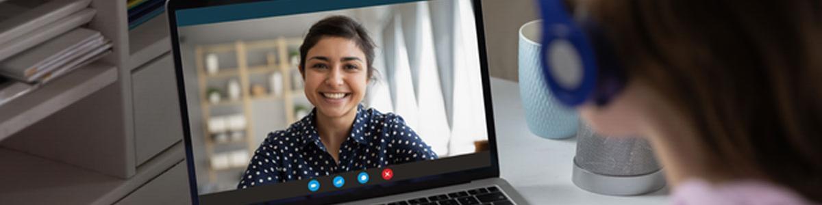 Person with headset viewing a video call on laptop.