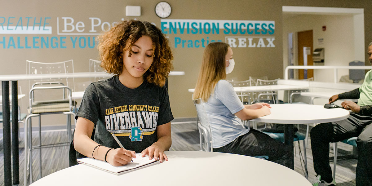 Female student in writing in notebook in study room