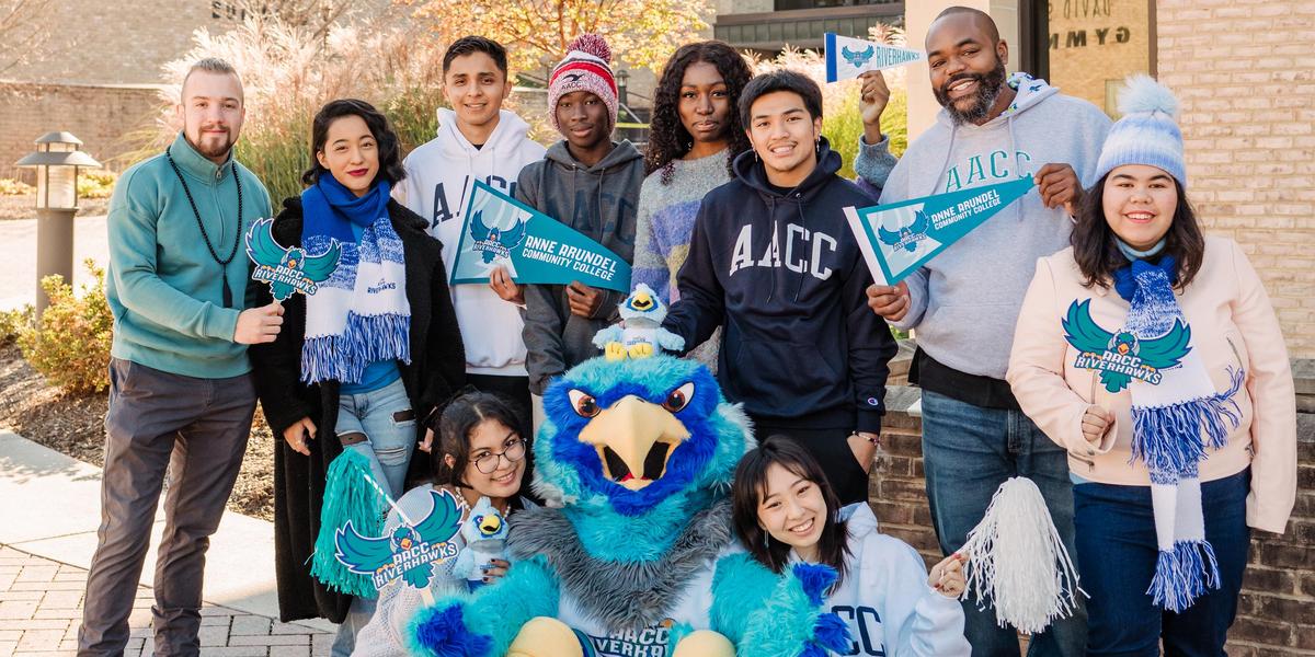 Students laughing and posing with AACC mascot, Swoop.