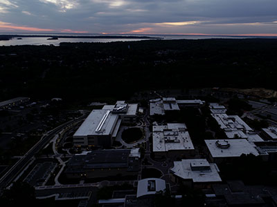 Aerial view of campus at dusk with sunset and water views in background